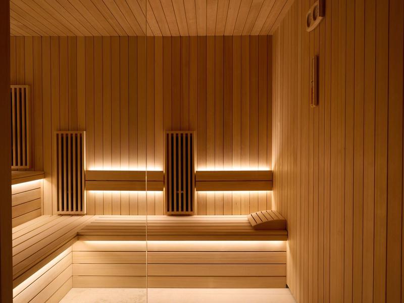 Moderní dřevěný interiér sauny s nepřímým osvětlením a opěrkami hlavy.