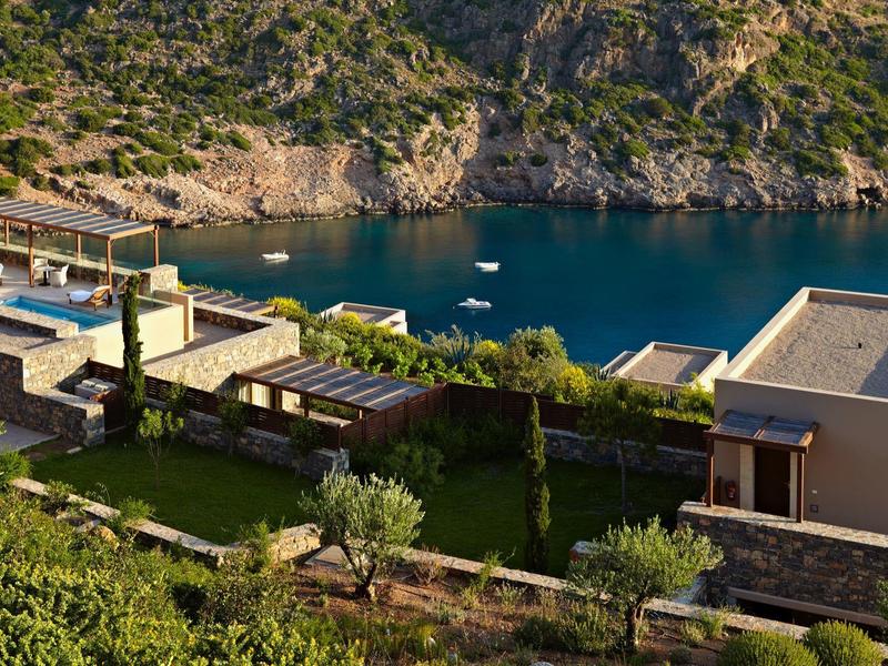 Moderní domy se zahradami na svahu s výhledem na zátoku s modrou vodou a loděmi