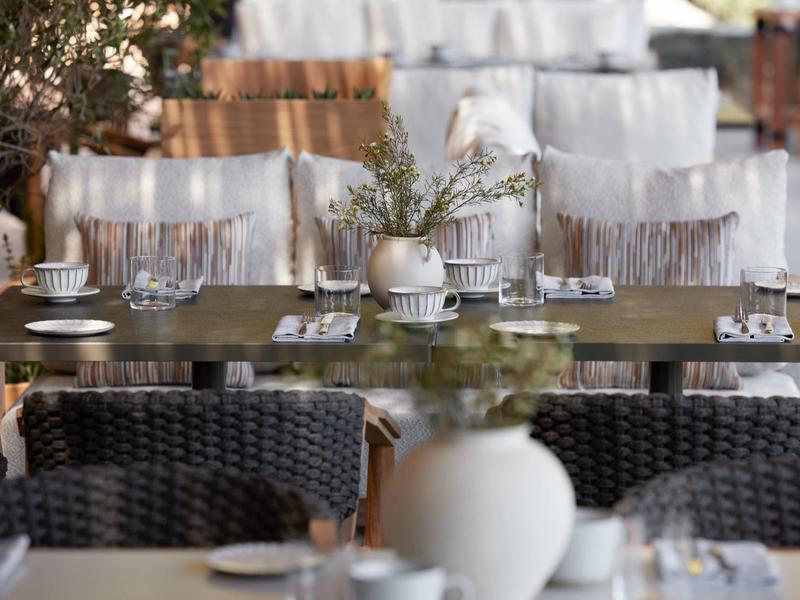 Elegantní jídelní stůl v restauraci s bílými potaženými židlemi a minimalistickou dekorací stolu.