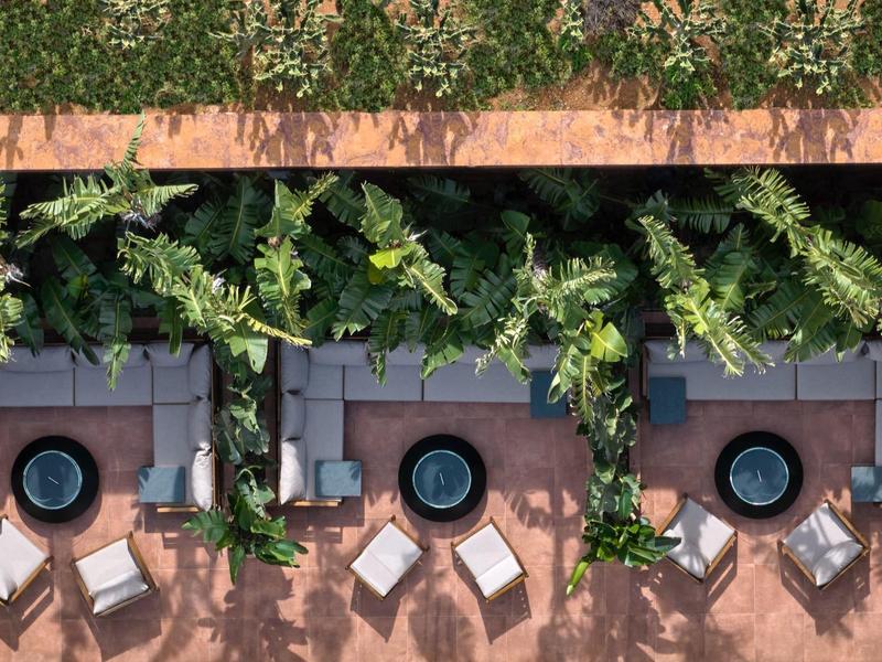 Tři kruhové bazény obklopené lehátky pod zeleným listnatým baldachýnem.