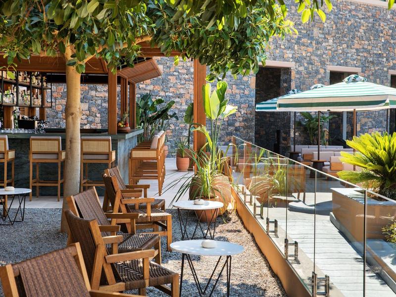 Pohodlná venkovní terasa hotelu s dřevěným nábytkem a slunečníky.