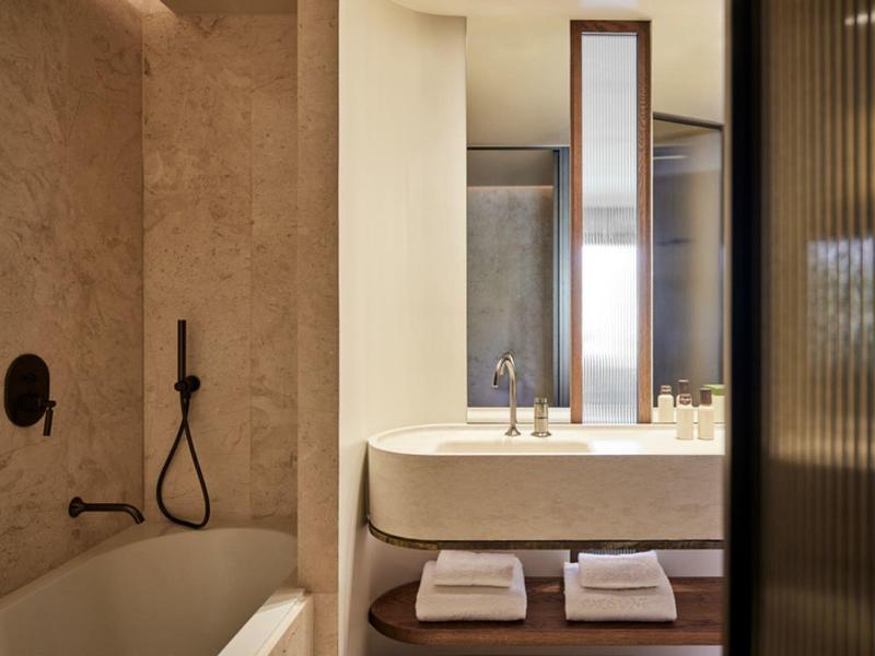 Moderní koupelna s vanou, sprchovou hlavicí a umyvadlem se zrcadlem