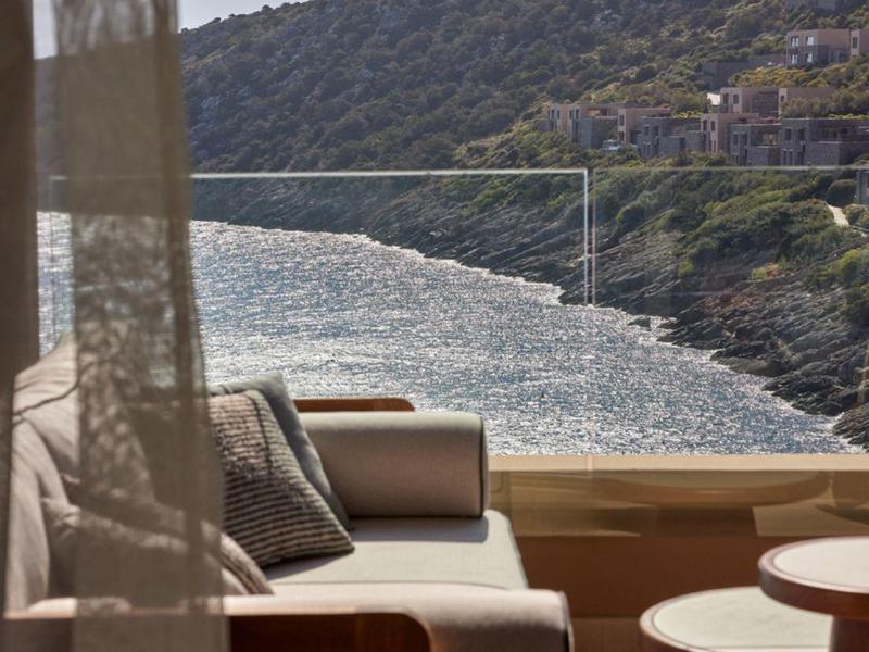 Pohodlný sedací kout na terase s výhledem na pobřeží a moře za slunečného počasí.