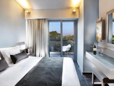 Modernes Schlafzimmer mit großem Bett, grauen Textilien, Balkon und hellen Wänden.