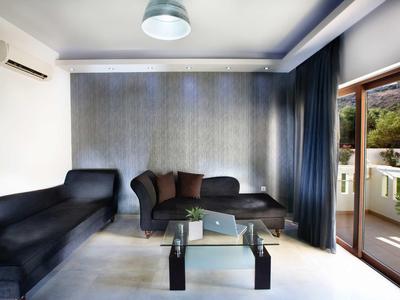 Moderner Wohnzimmerbereich mit schwarzen Sofas, Glas-Couchtisch und großem Balkon im Hintergrund.