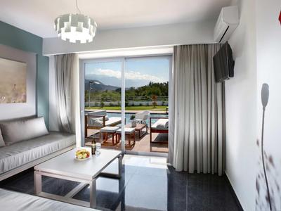 Helles Wohnzimmer mit großer Glas-Schiebetür, grauem Sofa, kleinem Holztisch und Blick auf Berglandschaft.