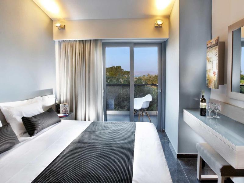 Modern hotelkamer met tweepersoonsbed, balkon en uitzicht op bomen.