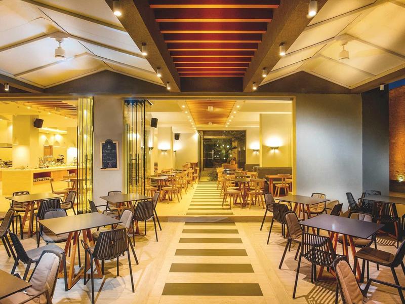 Modern restaurant met houten tafels en stoelen in helder verlichte ruimte.