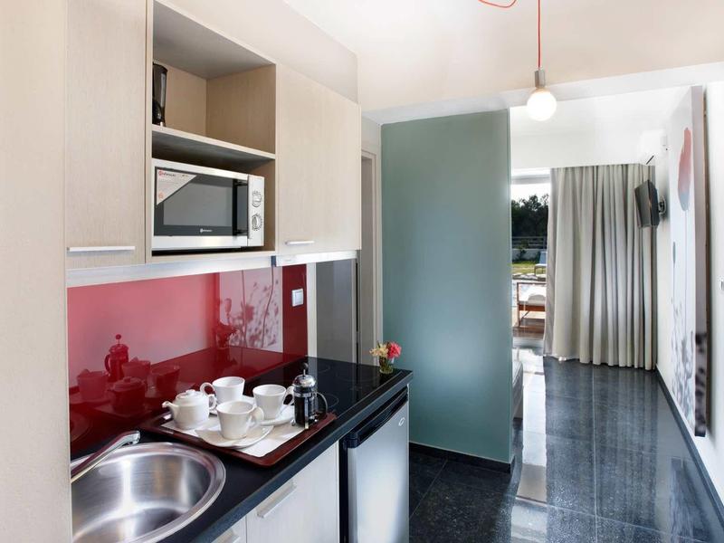 Moderne hotelkeuken met magnetron, koffiezetapparaat en gootsteen in lichte ruimte.