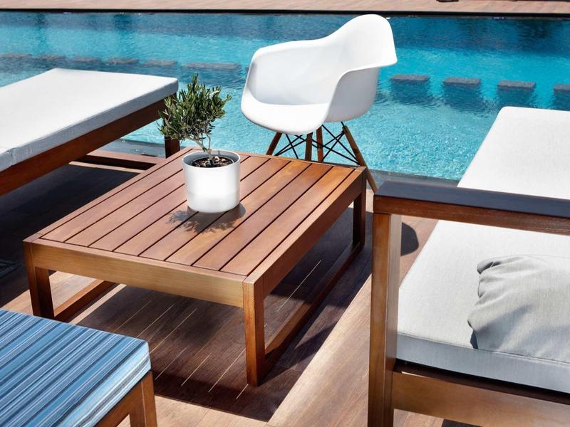 Moderne houten terras met comfortabele witte stoelen en uitzicht op het zwembad.