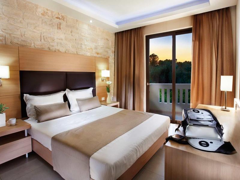 Modern hotelkamer met groot bed, bureau en uitzicht op zonsondergang.