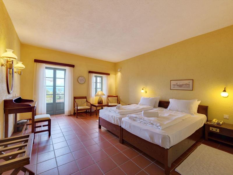 Habitación de hotel luminosa con dos camas individuales y acceso a un balcón.