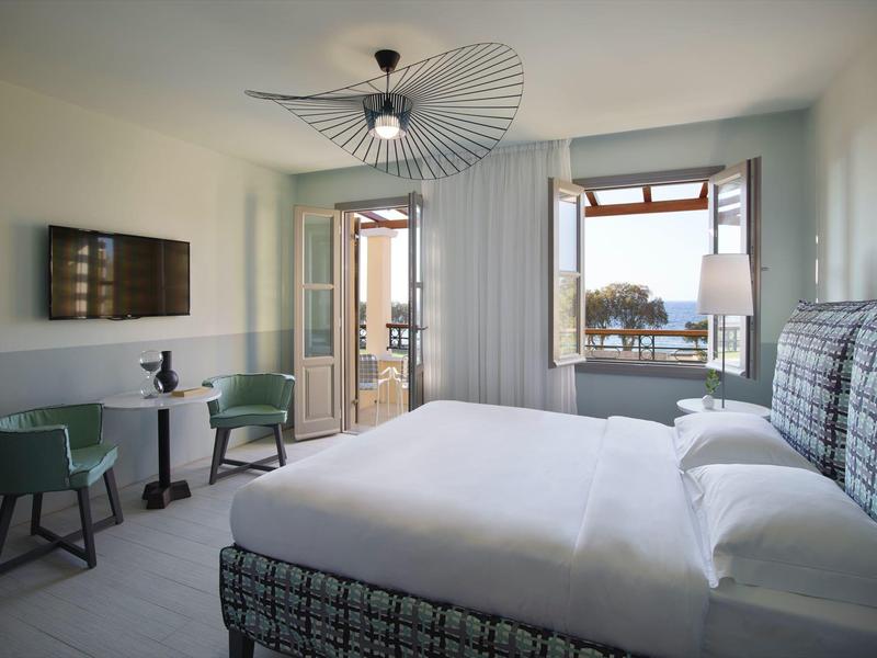 Habitación de hotel moderna con cama grande, balcón y vista al mar.