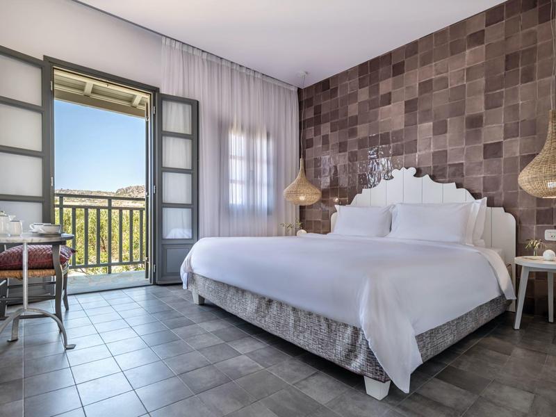 Dormitorio luminoso con cama doble, pared de acento y balcón con vista.