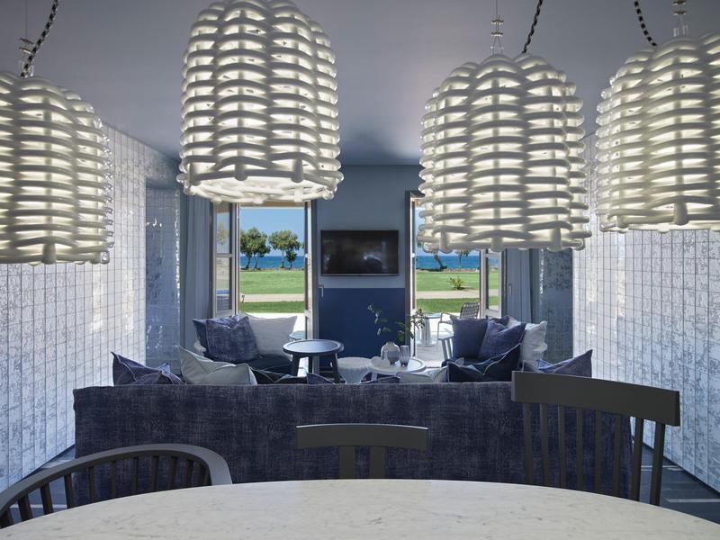 Salón moderno con elegantes lámparas colgantes y vista a la piscina y jardín.