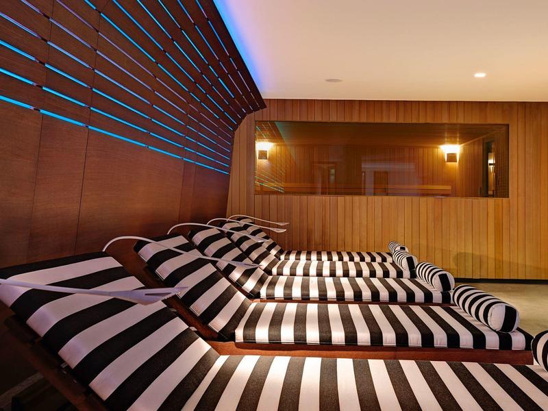 Varias tumbonas con rayas negras y blancas en una sala de descanso moderna con revestimiento de madera.