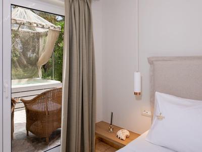 Przytulny pokój hotelowy z łóżkiem, stolikiem nocnym i widokiem na taras z krzesłami.