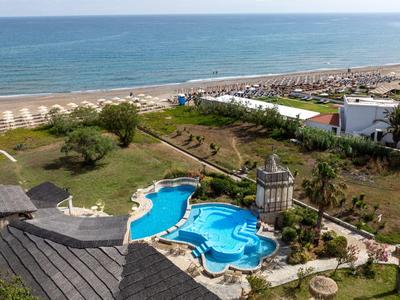 Widok na basen i kompleks hotelowy bezpośrednio przy plaży z parasolami i morzem w tle