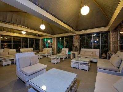 Przytulny salon z wygodnymi fotelami i stołami w dobrze oświetlonym pawilonie.