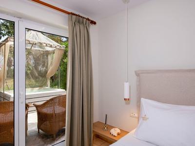 Nowoczesny pokój hotelowy z tarasem i zielonym widokiem przez szklane drzwi.