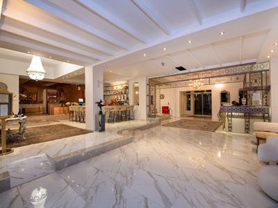 Jasna lobby hotelowa z marmurową podłogą, miejscem do siedzenia i nowoczesnym oświetleniem.