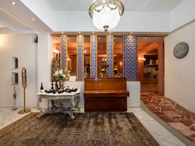 Elegancki korytarz hotelowy z antyczną ławką, stołem z kwiatami i dużą lampą wiszącą.