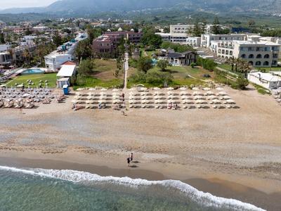 Plaża z leżakami przed hotelami i górami w tle