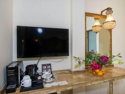 Nowoczesny serwis kawowy i telewizor w jasnym pokoju hotelowym z drewnianym stołem i kwiatową dekoracją.