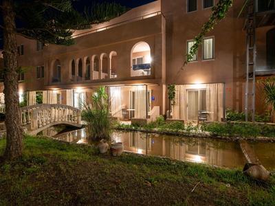 Oświetlony budynek hotelu z mostkiem nad małym kanałem wodnym nocą.