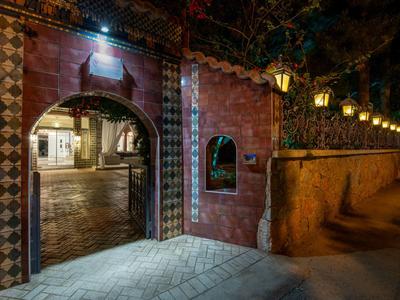 Oświetlone przejście z wzorzystymi kafelkami i latarniami przy brukowanej ulicy nocą.