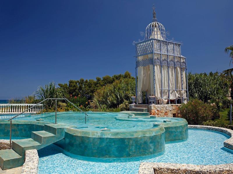 Niebieski basen z wodospadem i białą wieżą w tle pod czystym niebem