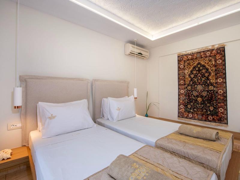 Nowoczesny pokój hotelowy z dwoma pojedynczymi łóżkami, dywanem na ścianie i pośrednim oświetleniem sufitowym.