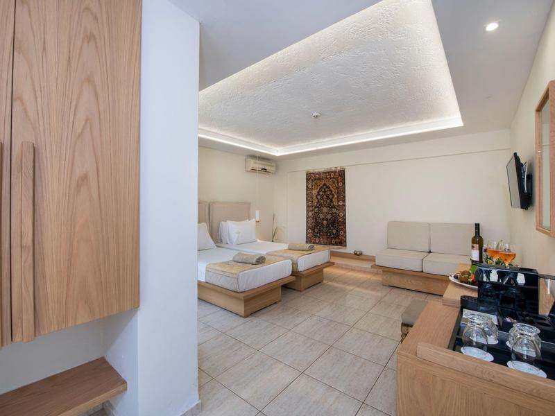 Jasny pokój hotelowy z łóżkiem podwójnym, miejscem do siedzenia, telewizorem i minibarem na kafelkowanej podłodze.