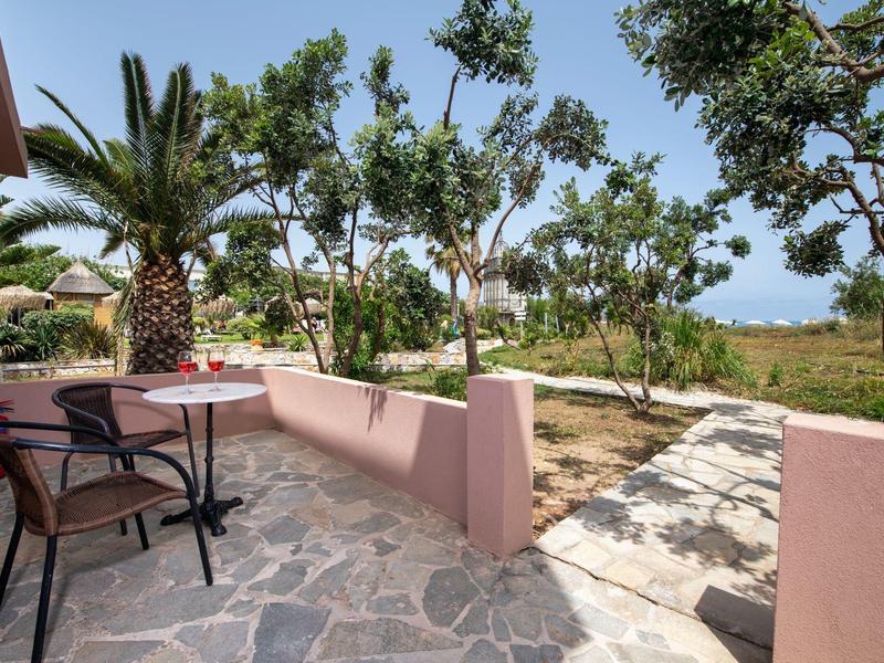 Miejsce do siedzenia z krzesłami i stołem na tarasie z widokiem na ogród i morze.