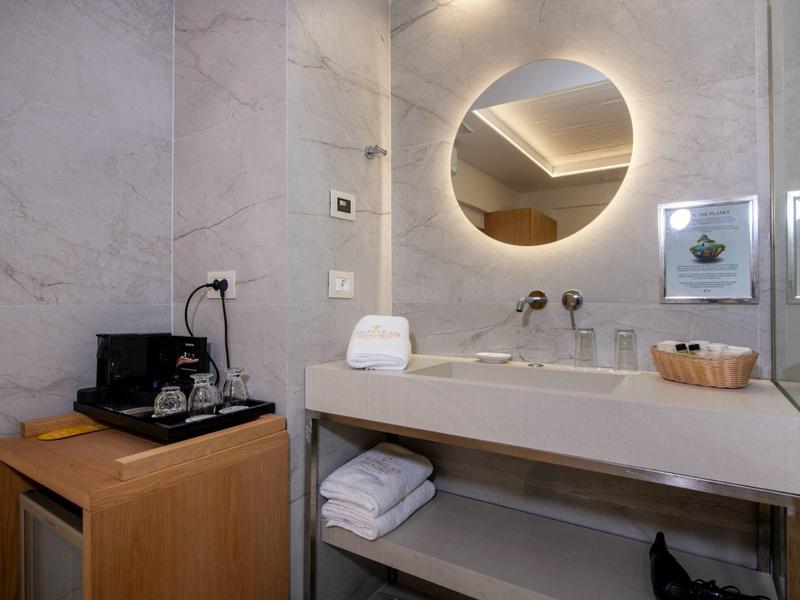 Nowoczesna łazienka z okrągłym podświetlanym lustrem, umywalką i ręcznikami.