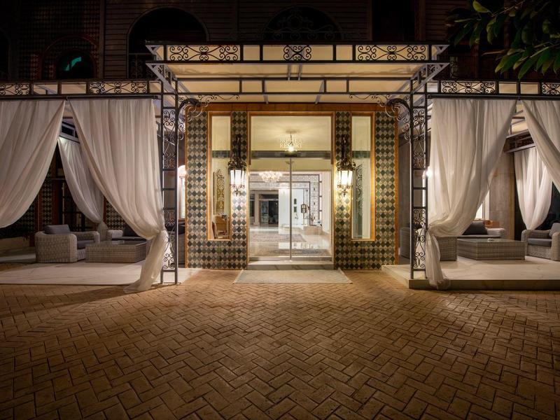 Oświetlone wejście do hotelu z dwoma przytulnymi miejscami do siedzenia i białymi zasłonami.