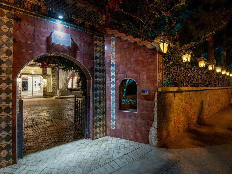 Oświetlone przejście z wzorzystymi kafelkami i latarniami przy brukowanej ulicy nocą.