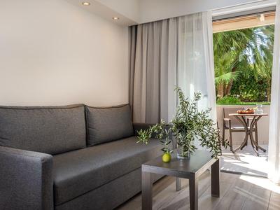 Cozy living area with gray sofa, small table, and balcony door overlooking greenery.