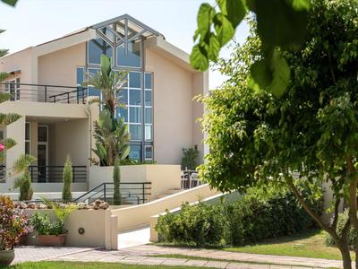 Modernes Hotelgebäude mit großen Fenstern und umliegendem Grün in sonniger Umgebung