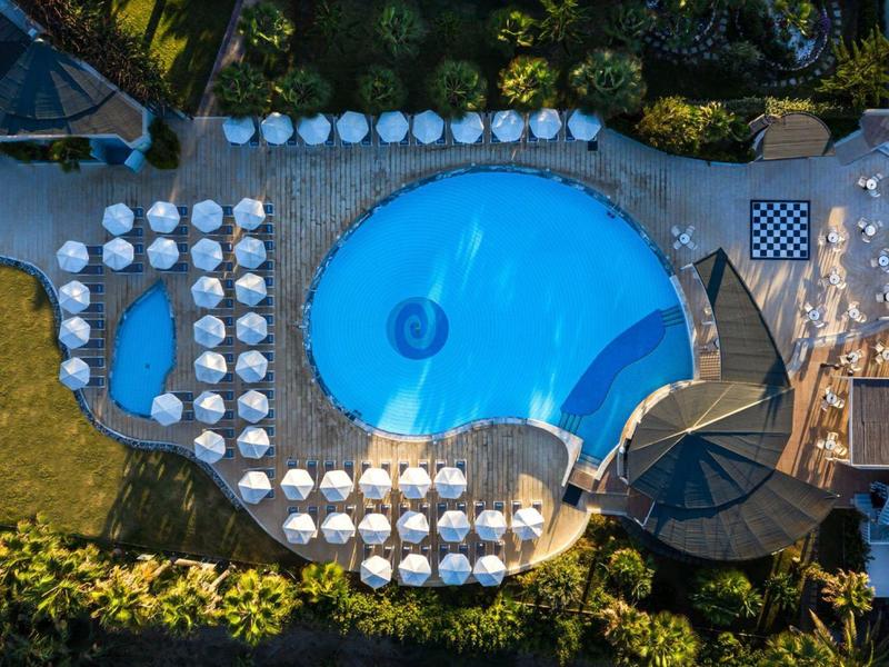 Aerial view of a round swimming pool with umbrellas and chairs around it.