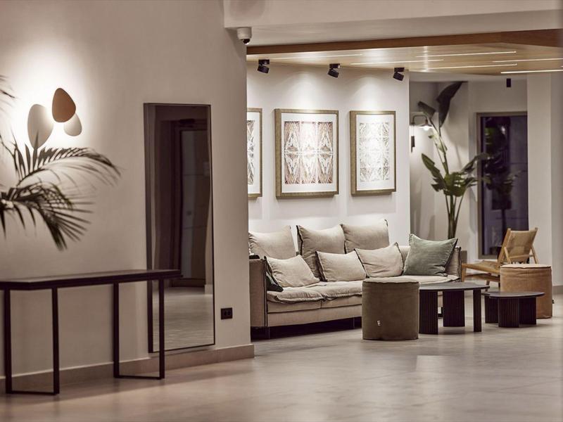 Cozy hotel lounge with sofa, cushions, framed art, plants, and soft lighting.