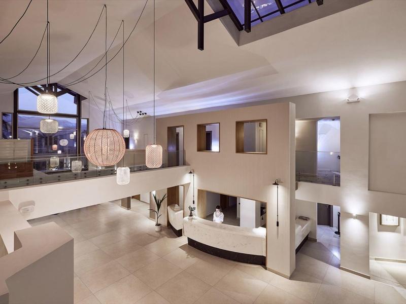 Spacious hotel lobby with modern white decor and hanging light fixtures