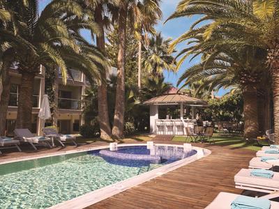 Hotelový bazén s slunečníky, lehátky a palmami za slunečného dne