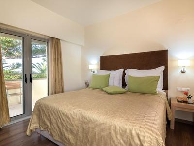 Cozy hotel room with a large bed, green pillows, nightstands, and a glass door to a balcony.