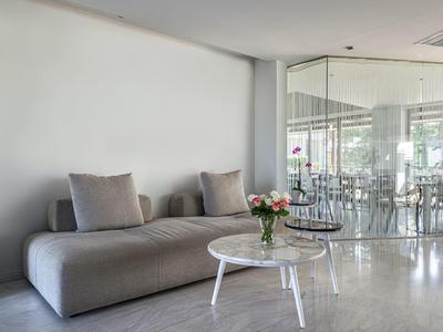 Modern lounge area with gray sofa, white coffee table, and glass-walled dining room in background.