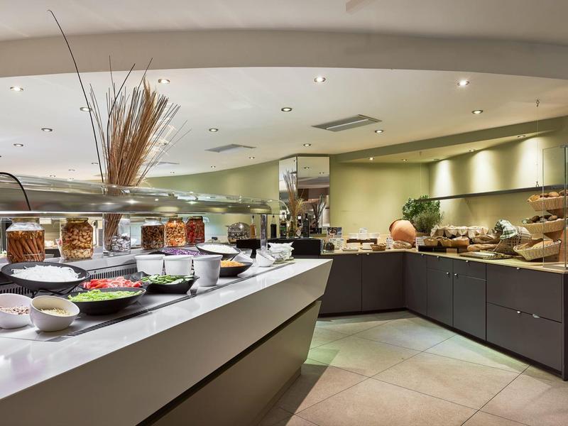 Modern buffet area with a variety of dishes and warm lighting in a hotel dining space.