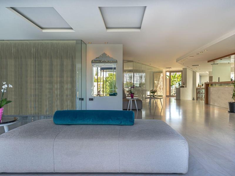 Bright hotel lobby with modern sofa, large windows, and plants