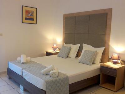 Przytulny pokój hotelowy z dwoma pojedynczymi łóżkami, stolikami nocnymi i łagodnym oświetleniem.