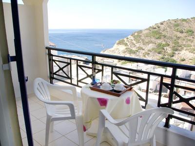 Balkon z białymi krzesłami i stolikiem, widok na morze w tle