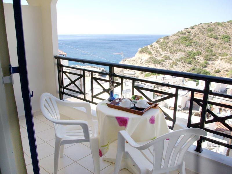 Balkon z białymi krzesłami i stolikiem, widok na morze w tle